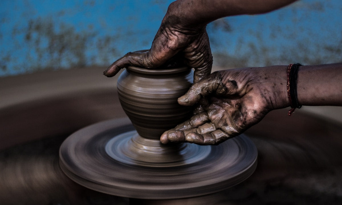 Mains d'artisan travaillant la céramique artisanale sur un tour de potier